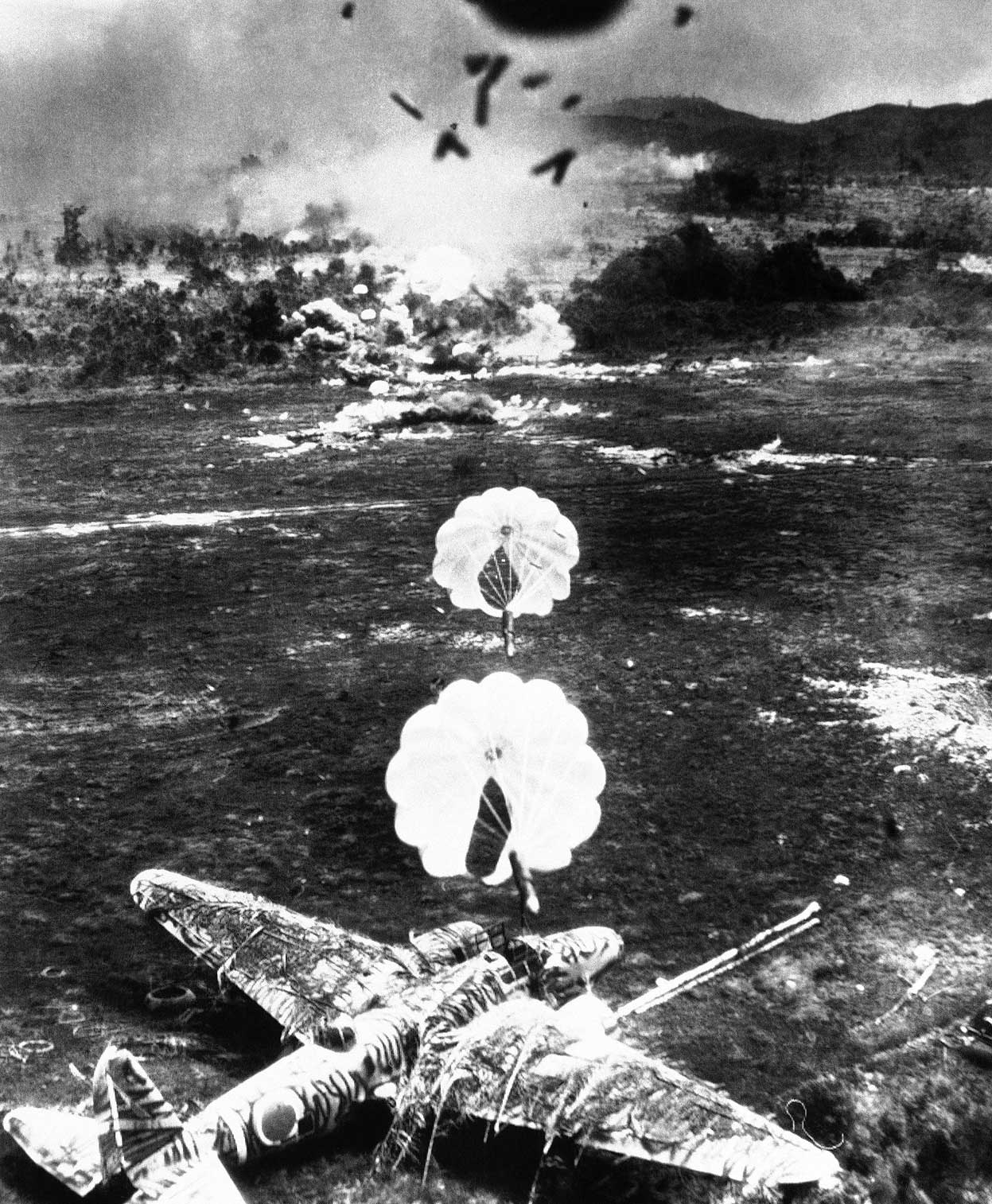 Американские парашютные бомбы поражают японские самолеты Mitsubishi Ki-21, "Sally", на аэродроме Old Namlea на острове Буру (Малайский архипелаг)